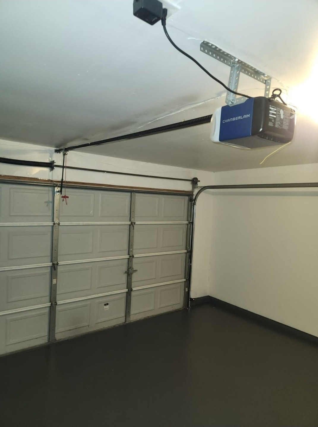 Chamberlain garage door opener mounted to a garage ceiling with rail and door